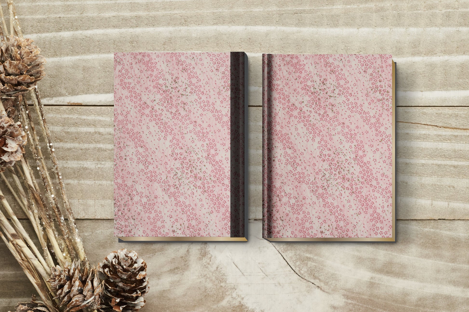 Two pink patterned books on a wooden surface with decorative elements.