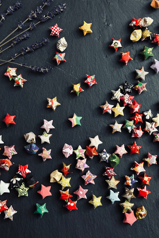 Colorful origami lucky stars made from chiyogami paper on a dark surface