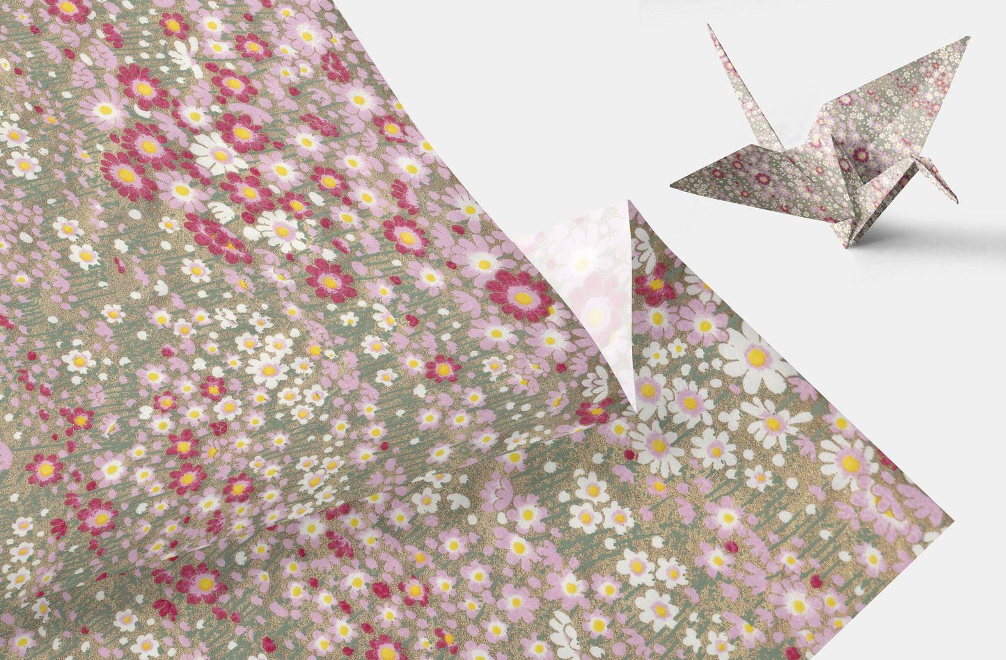 Floral-patterned chiyogami paper with a folded corner and an origami crane on a light background