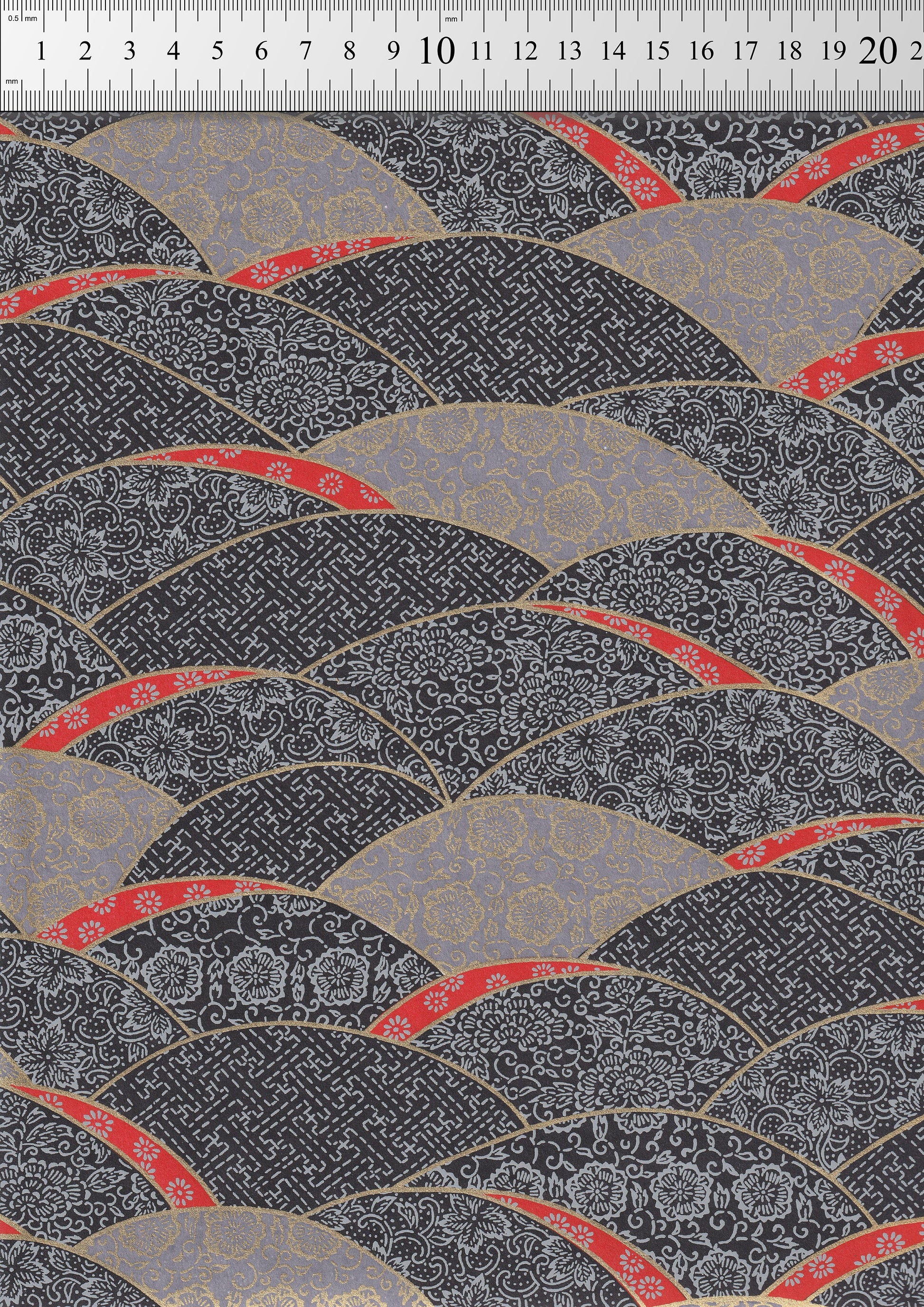 Patterned chiyogami paper with red, gray, and black design on a textured background
