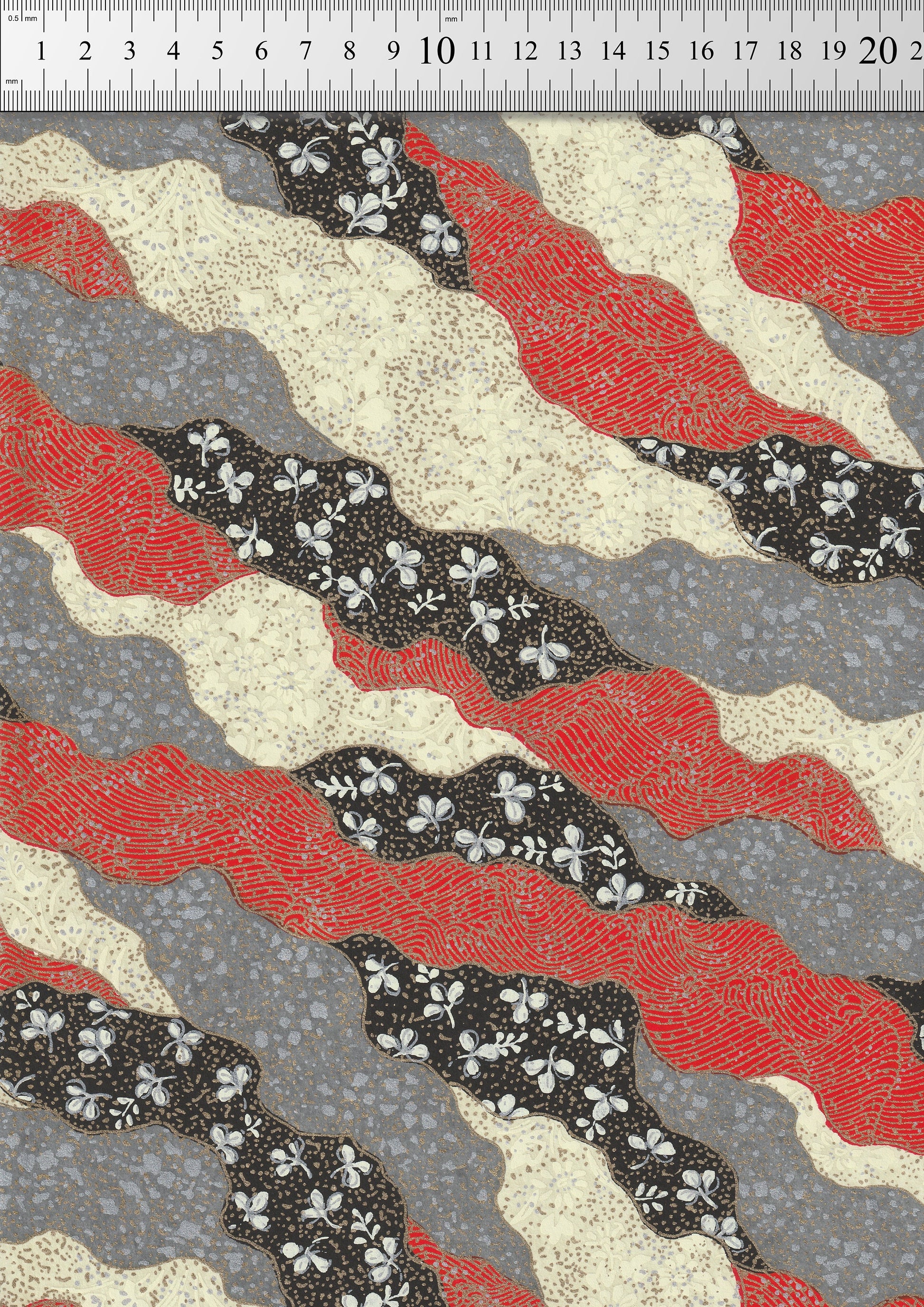 Chiyogami paper with red, black, and beige wavy pattern on a gray background with a ruler for scale.