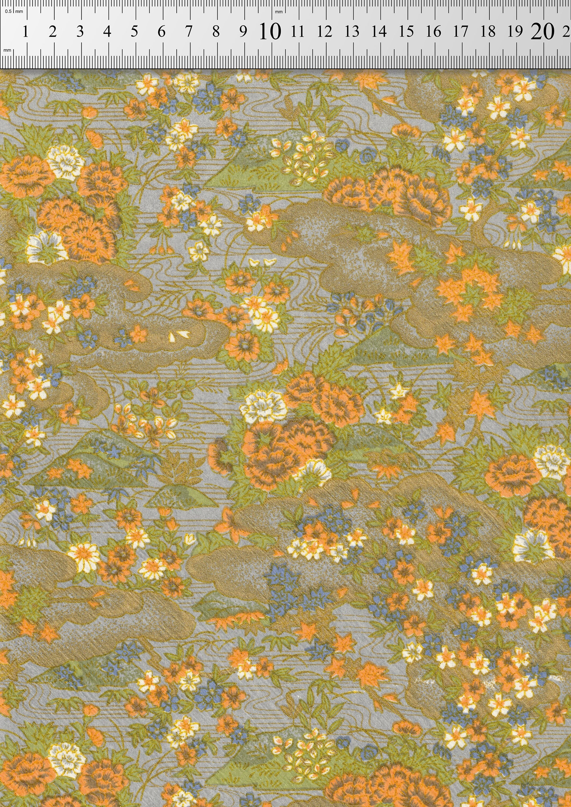 Floral chiyogami paper pattern with orange and green colors on a gray background, measured against a ruler.