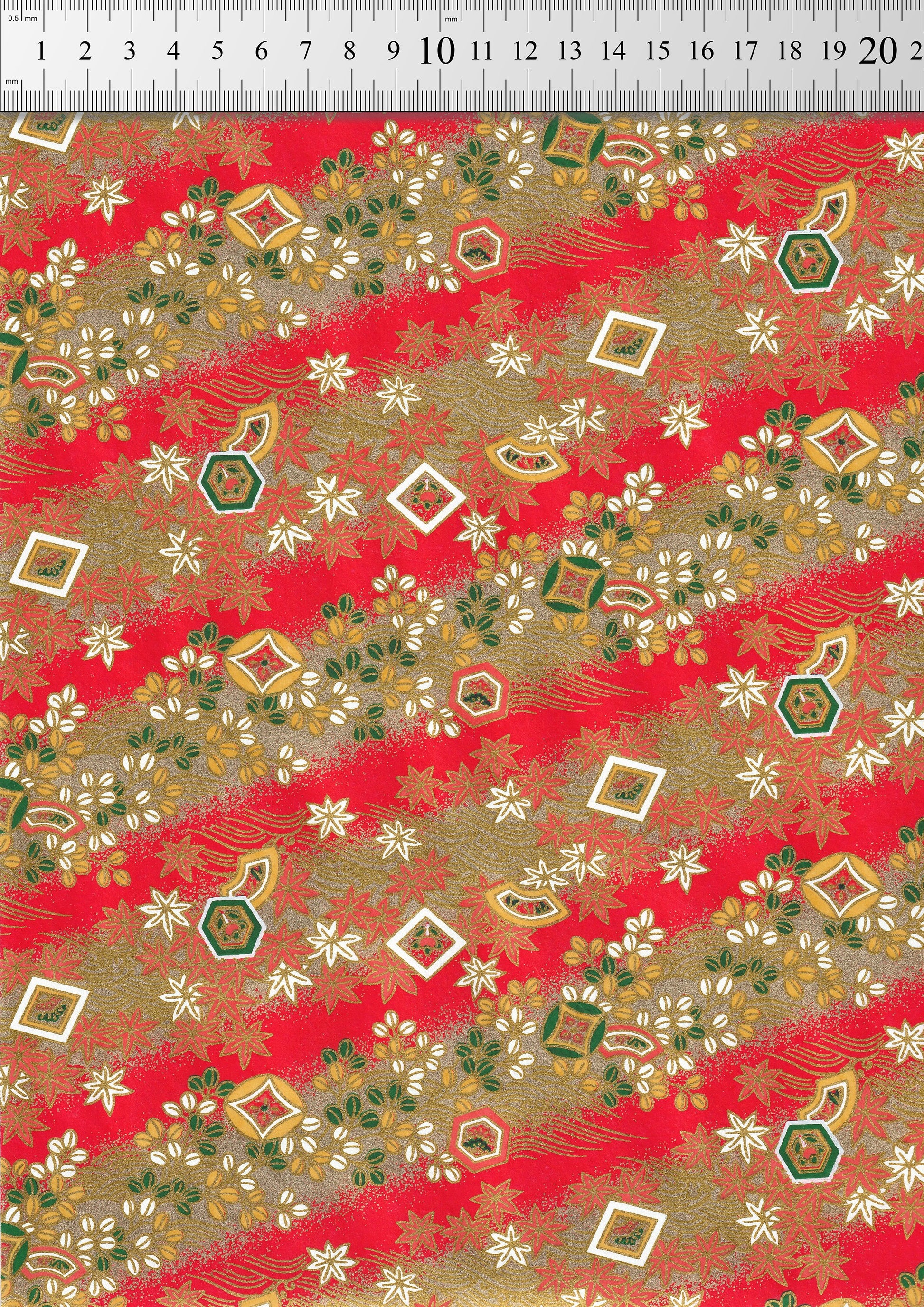 Decorative chiyogami paper with geometric patterns on a red background, measured against a ruler.