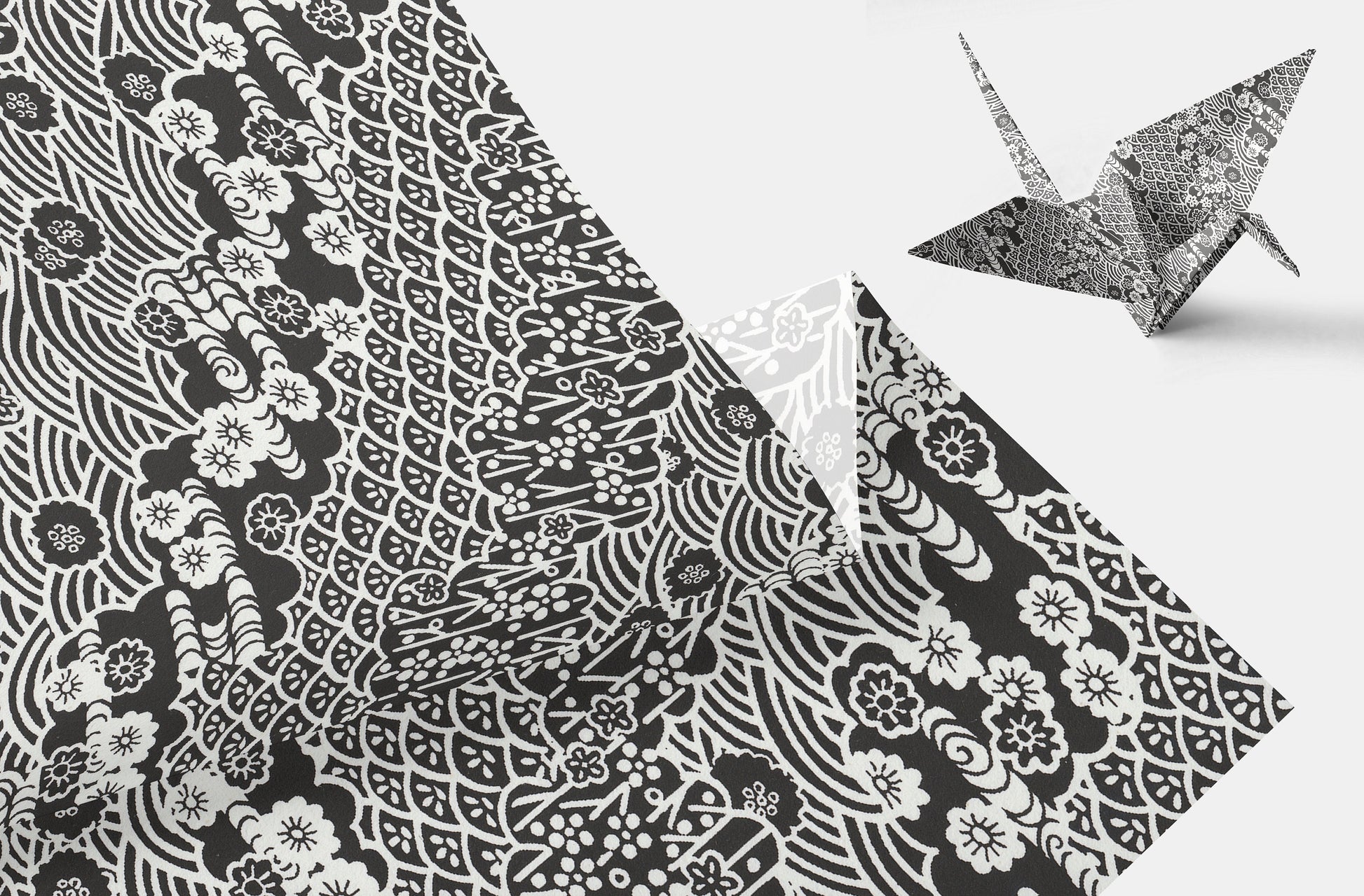 Black and white patterned  chiyogami paper with a folded paper crane on a light gray background