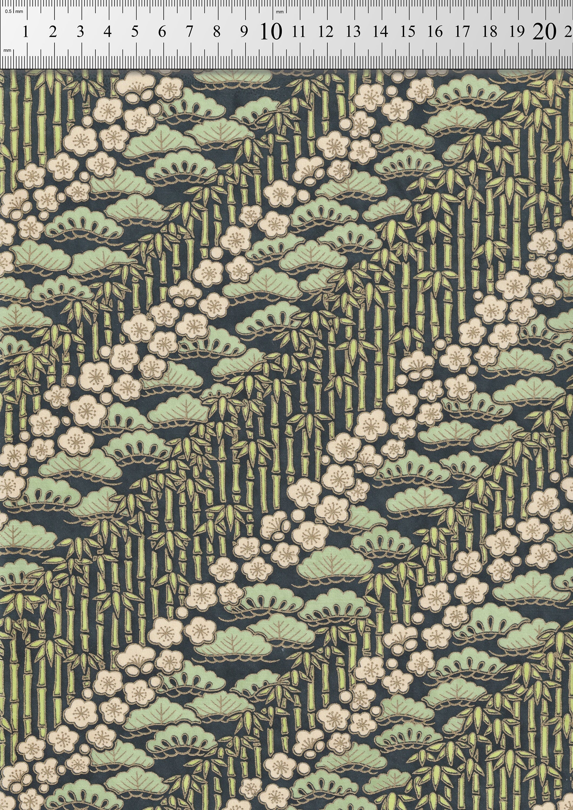Patterned chiyogami paper with green leaves and white flowers on a dark background with a ruler for scale