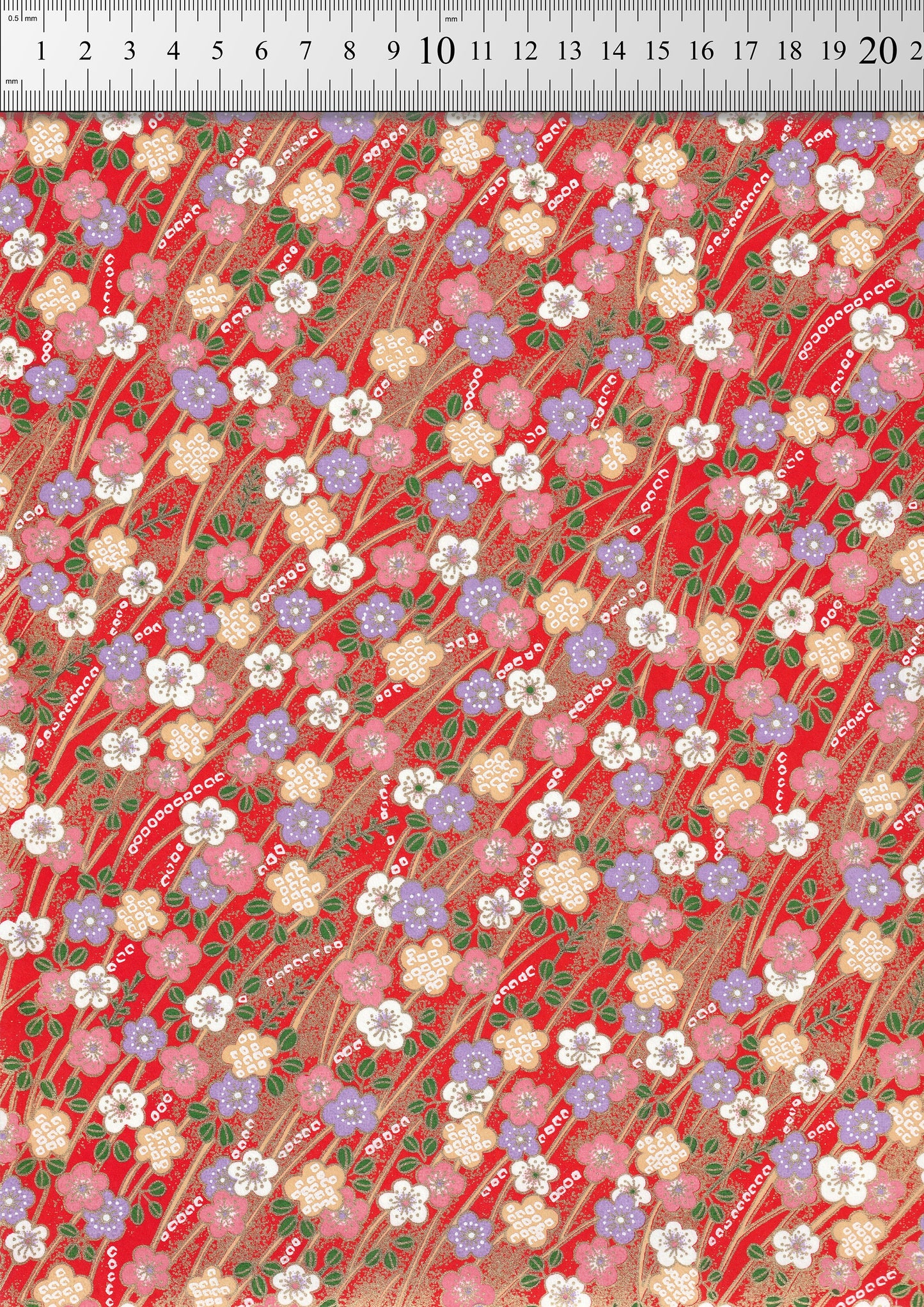 Floral patterned chiyogami paper with a ruler for scale on a red background