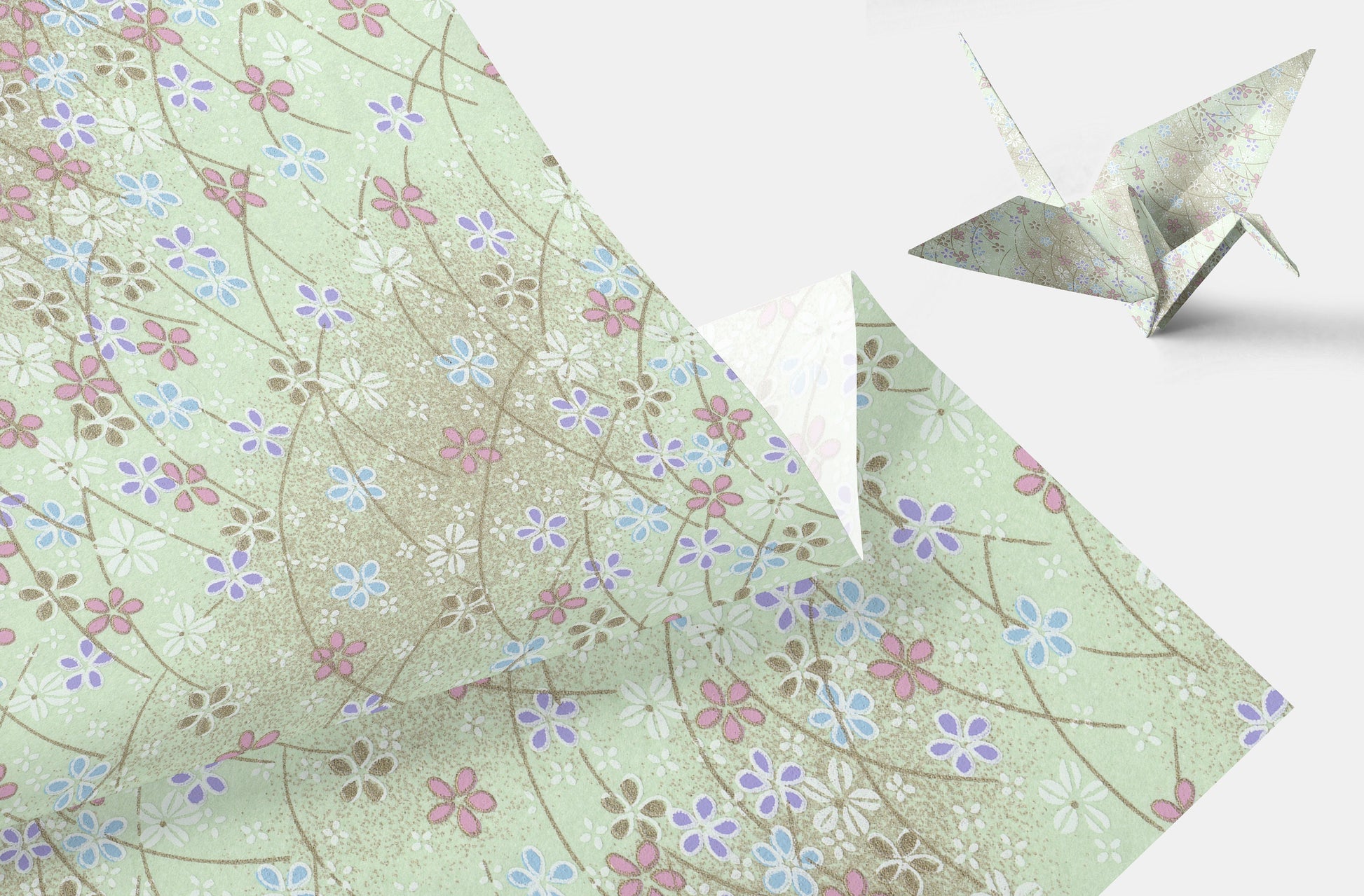 Floral-patterned paper with a folded paper crane on a light background