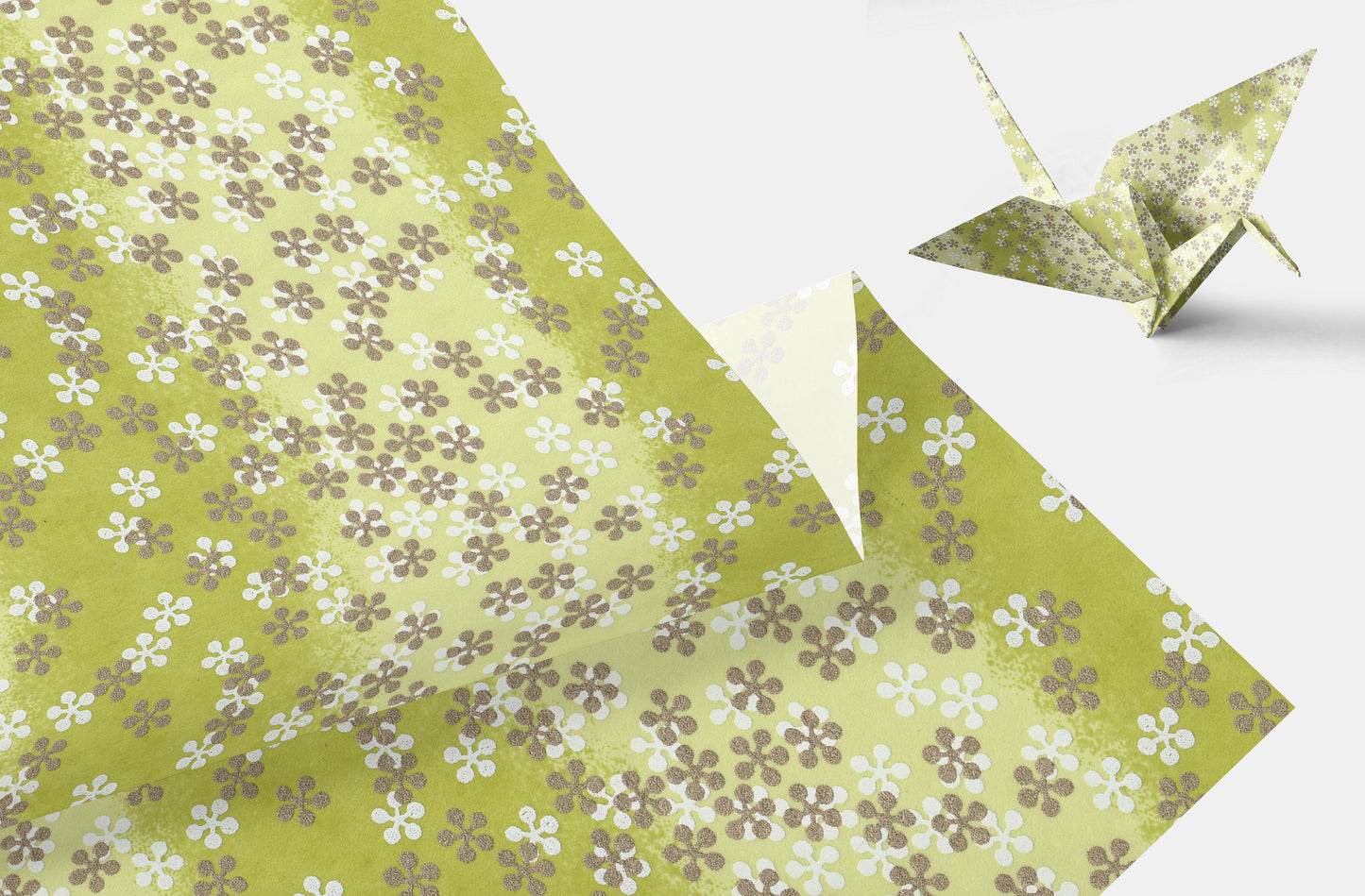 Green floral-patterned paper with a folded paper crane on a white background