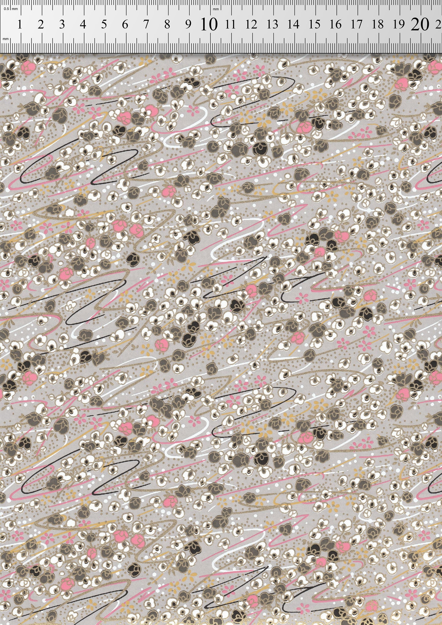 Patterned  chiyogami paper  with small flowers and lines on a gray background, measured against a ruler.