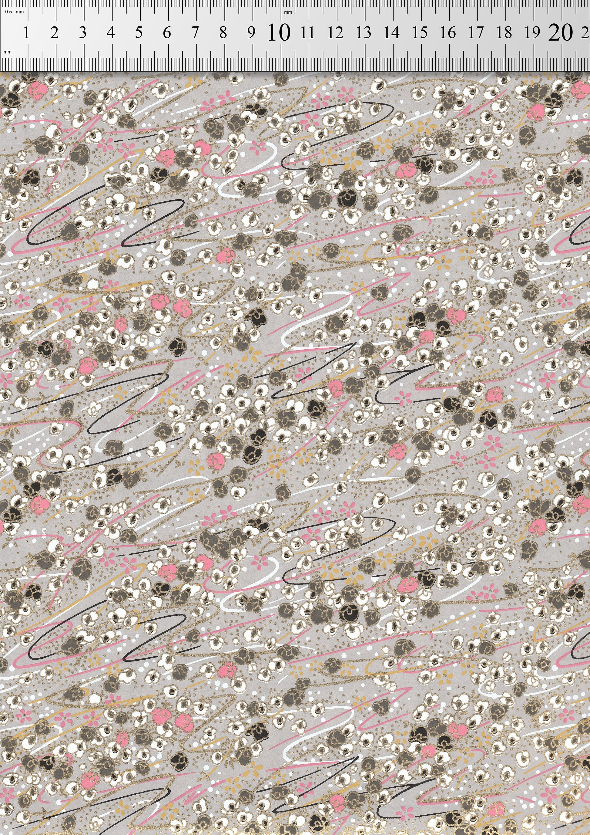 Patterned  chiyogami paper  with small flowers and lines on a gray background, measured against a ruler.