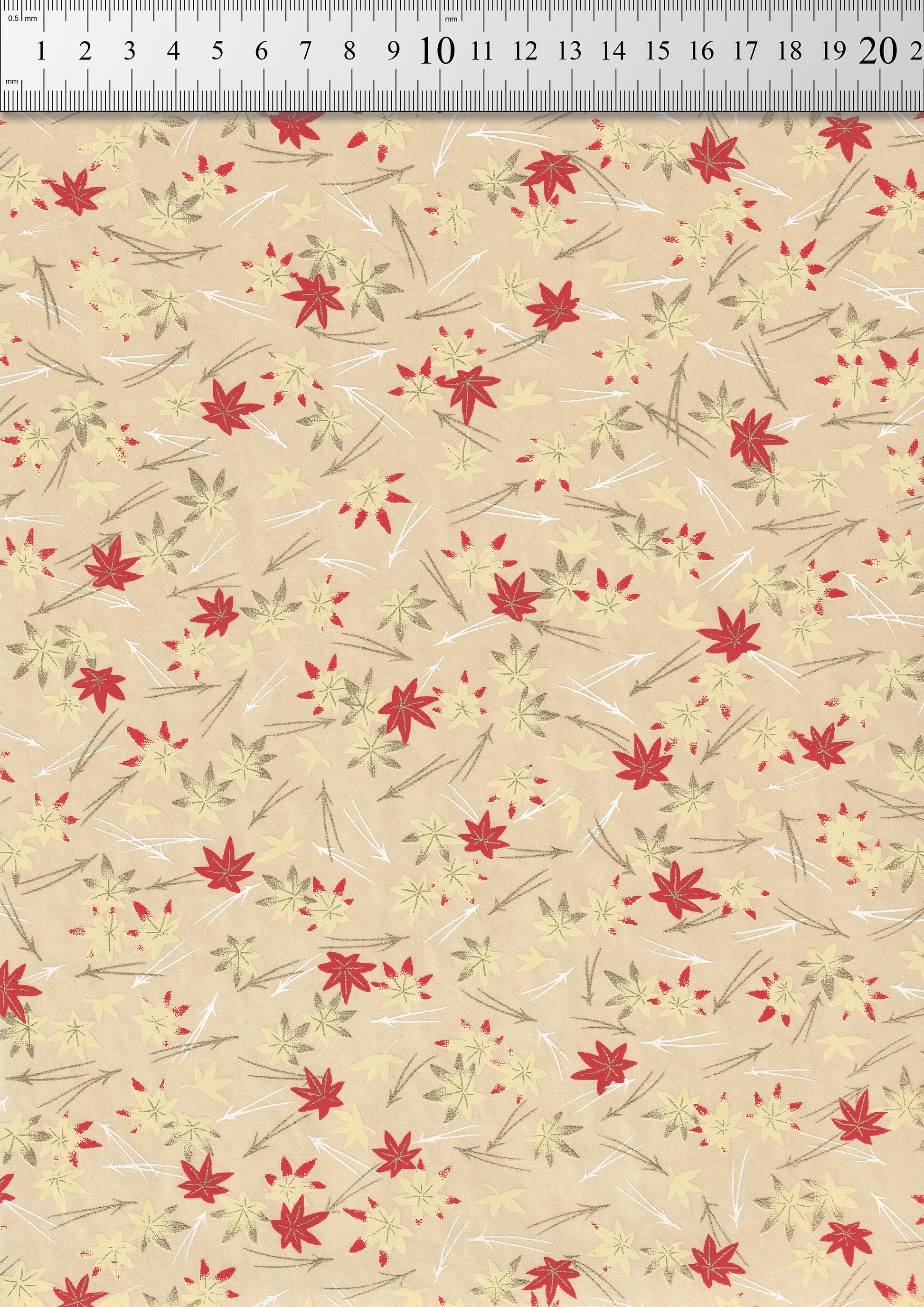 Floral patterned  chiyogami paper with red flowers and green leaves on a beige background, measured against a ruler.