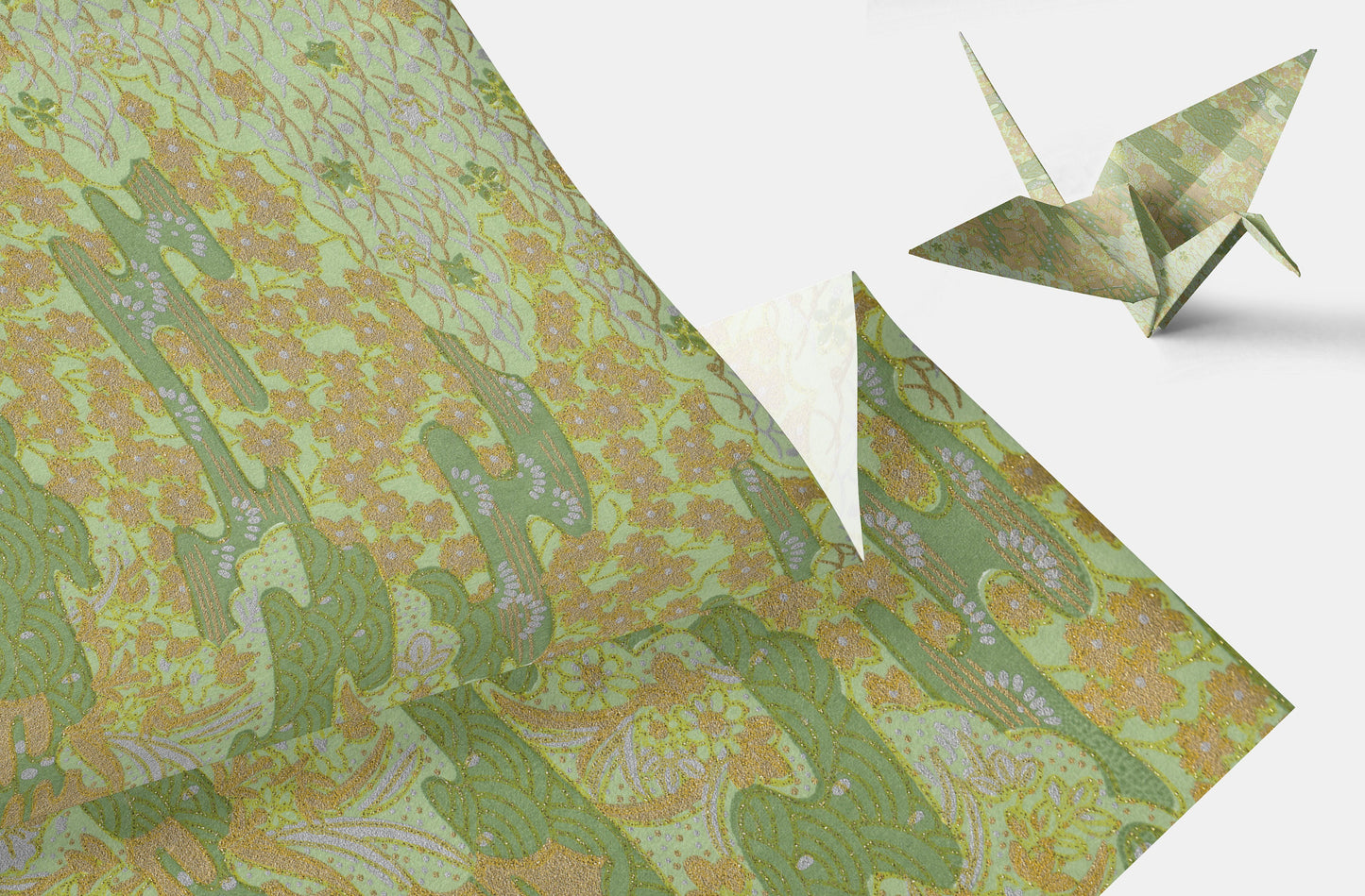 Green floral-patterned chiyogami paper with a folded origami crane on a white background
