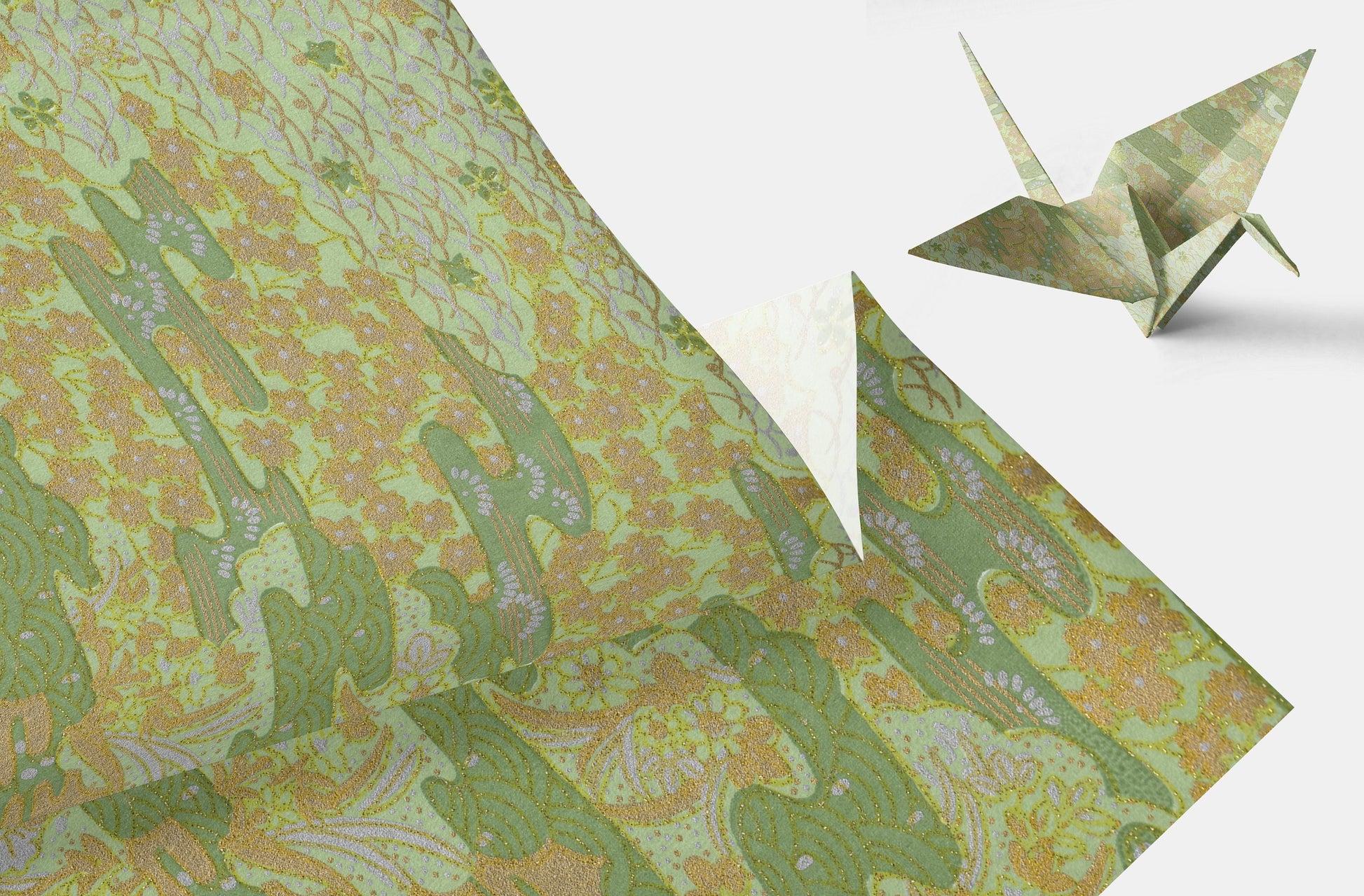 Green floral-patterned chiyogami paper with a folded origami crane on a white background