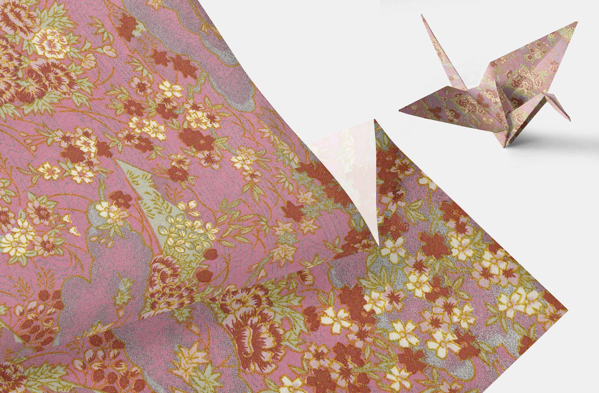 Floral-patterned chiyogami paper with a folded origami crane on a white background
