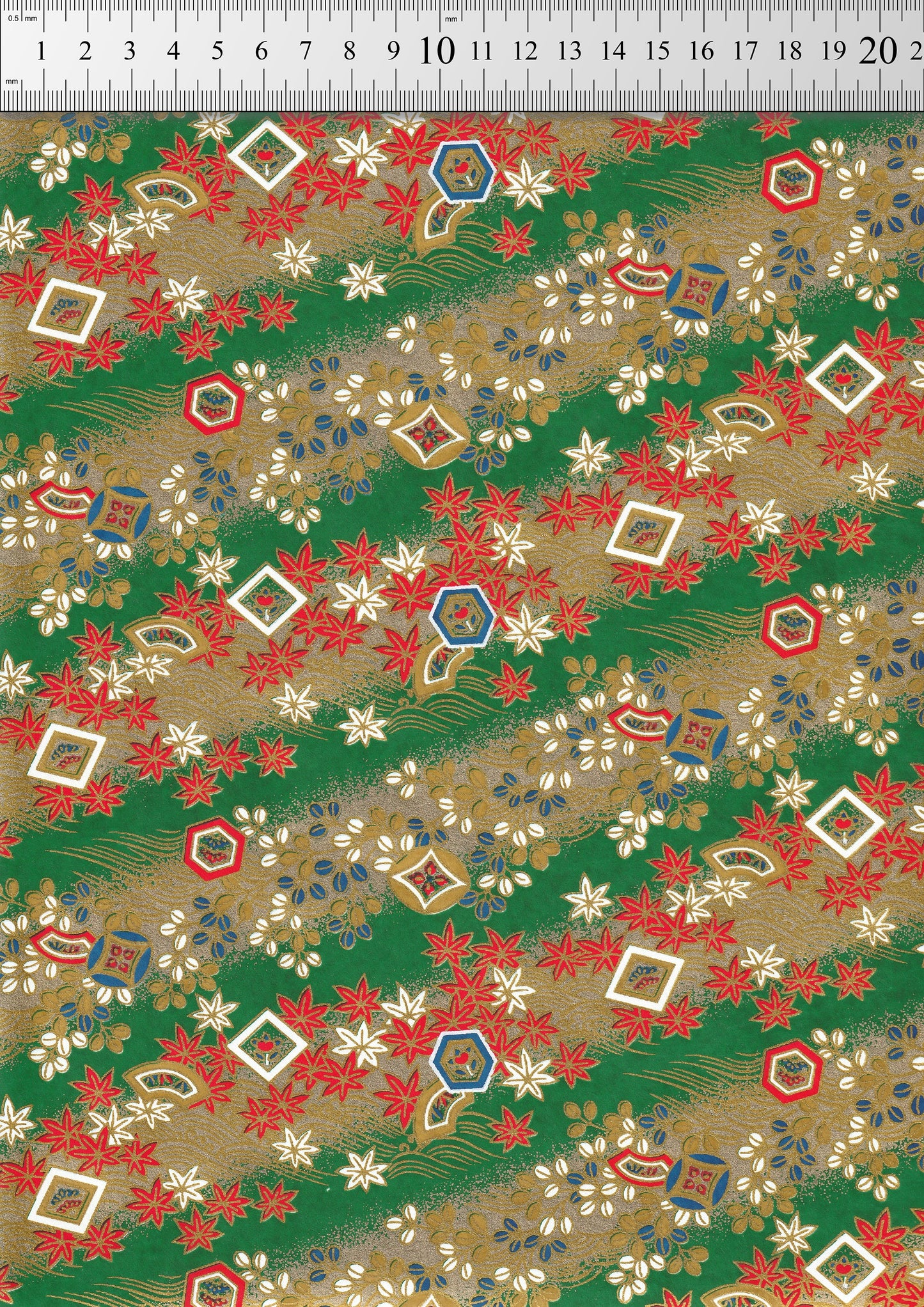Decorative chiyogami paper with a floral pattern on a green background, measured against a ruler.