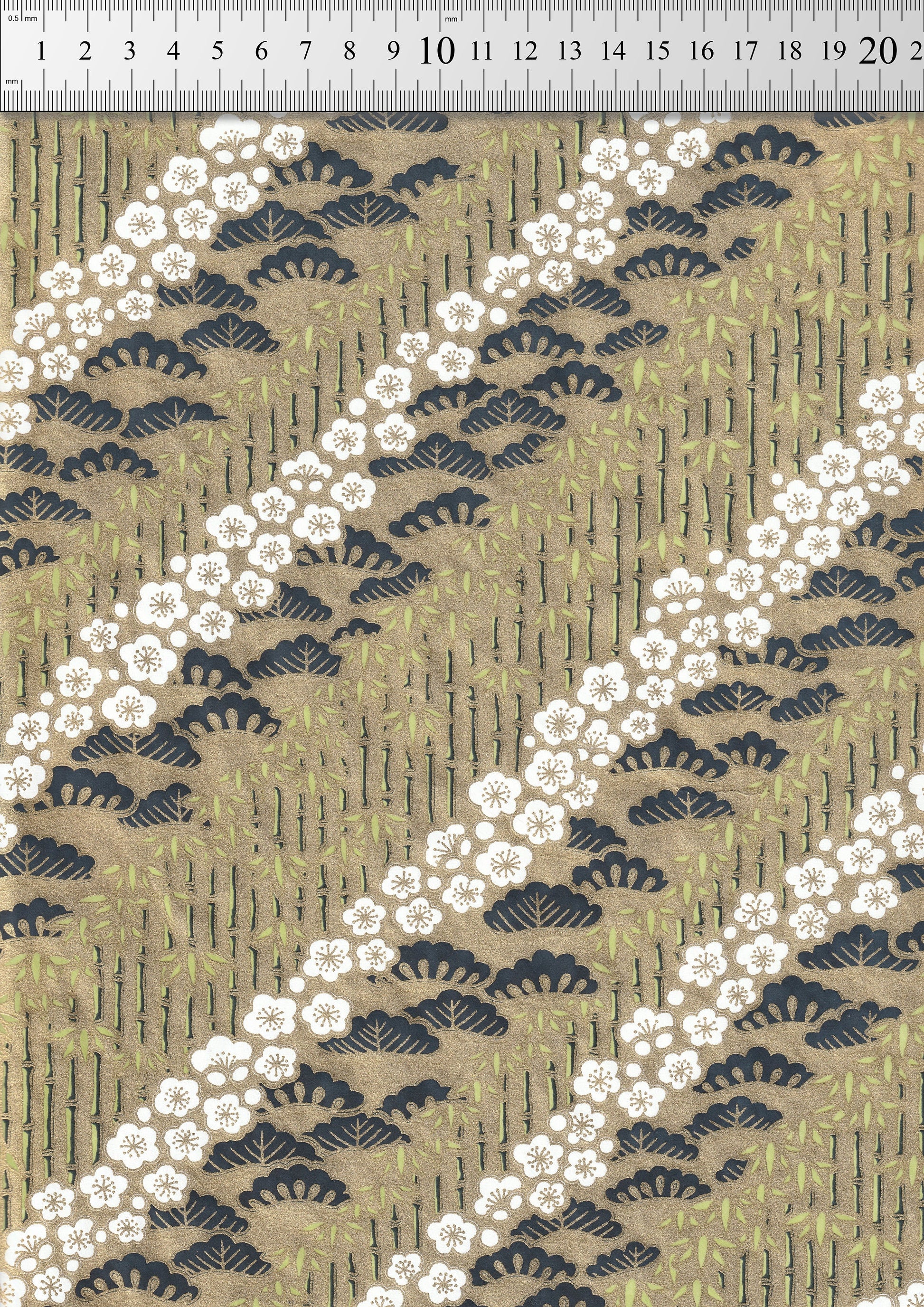 Decorative chiyogami paper with white floral pattern on a beige background with a ruler for scale