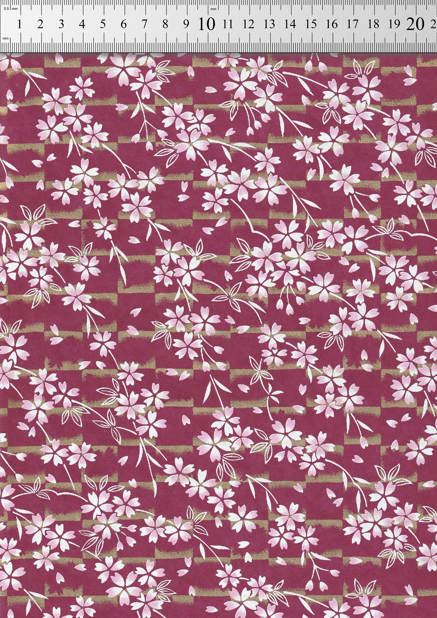 Floral pattern chiyogami paper with white flowers on a red background with a ruler for scale