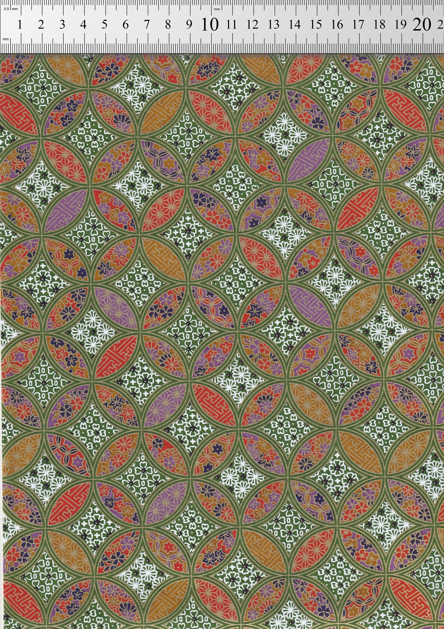 Patterned chiyogami paper with geometric design on a green background with a ruler for scale