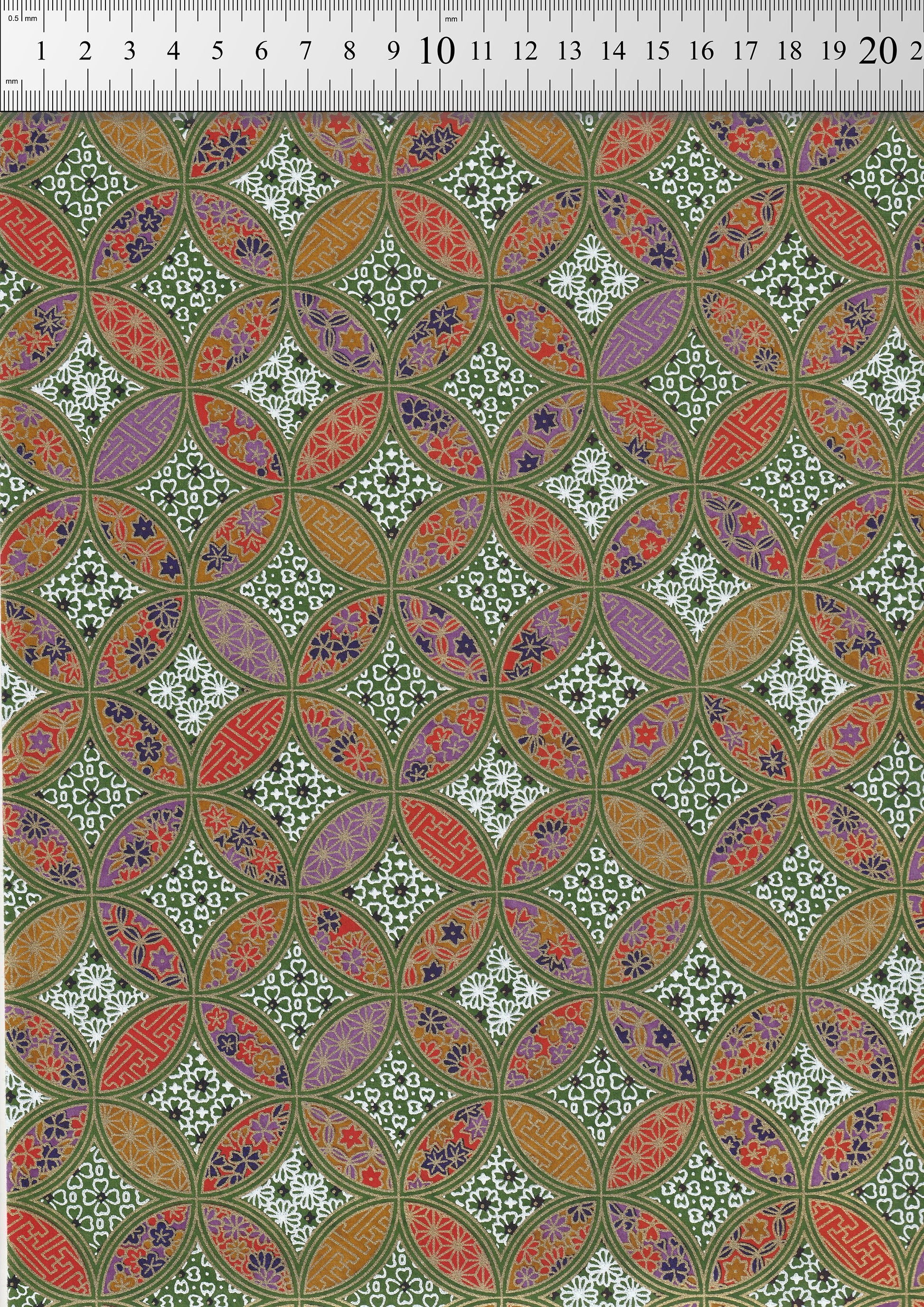 Patterned chiyogami paper with geometric design on a green background with a ruler for scale