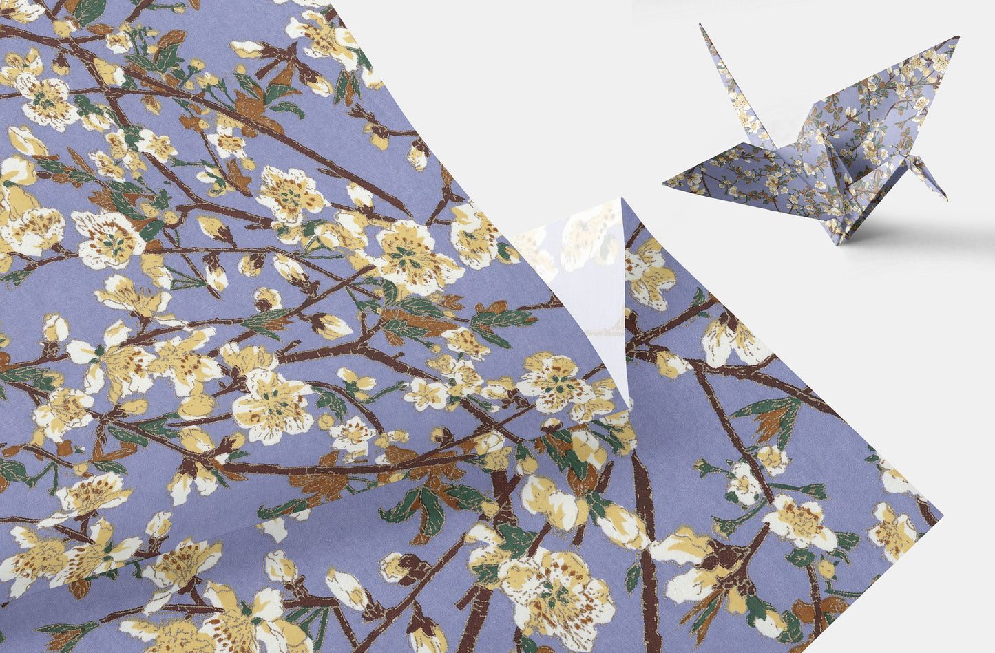 Floral patterned chiyogami paper with a folded corner and a paper crane on a white background