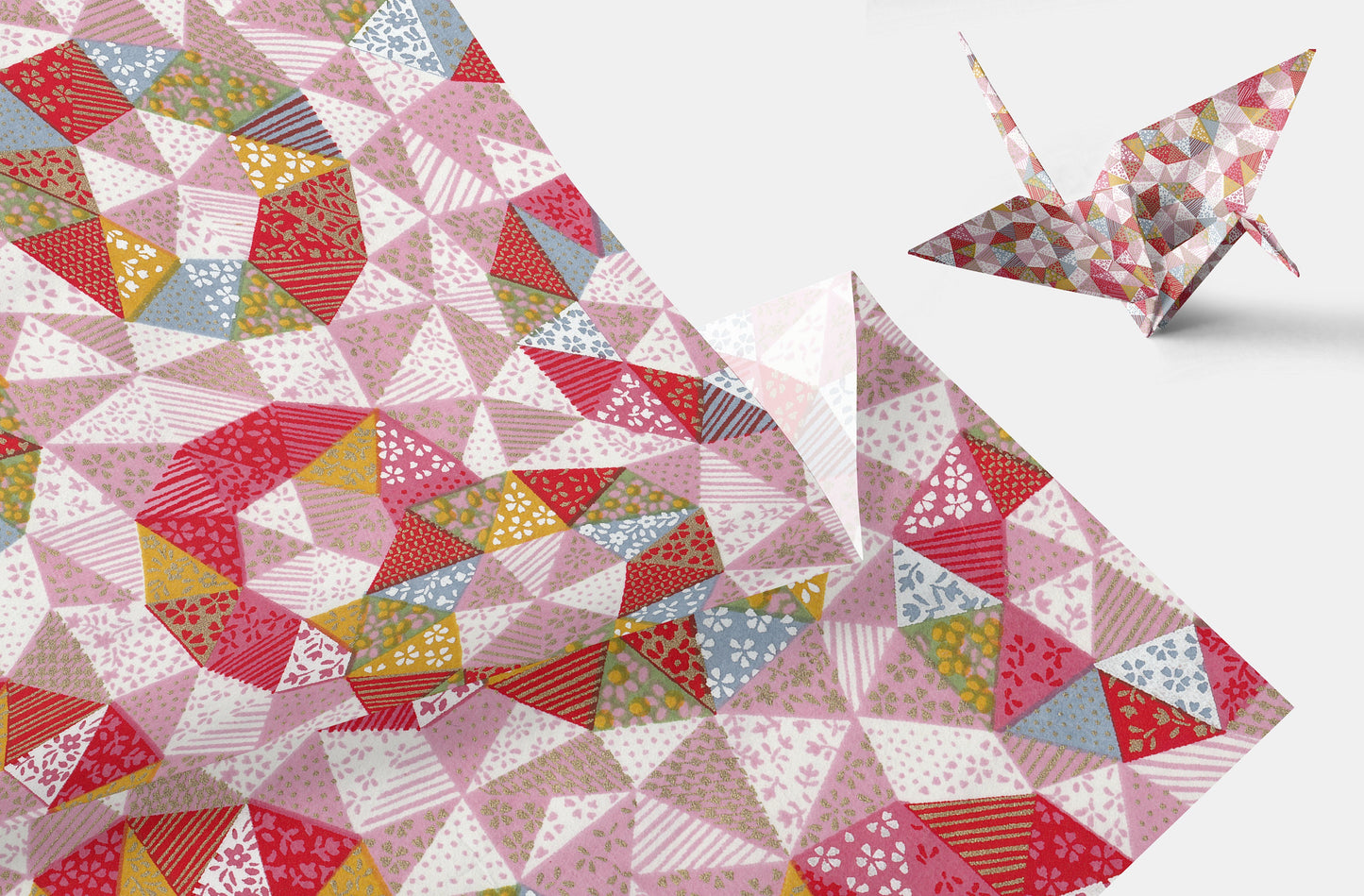 Colorful quilt with geometric patterns and a paper crane on a light background