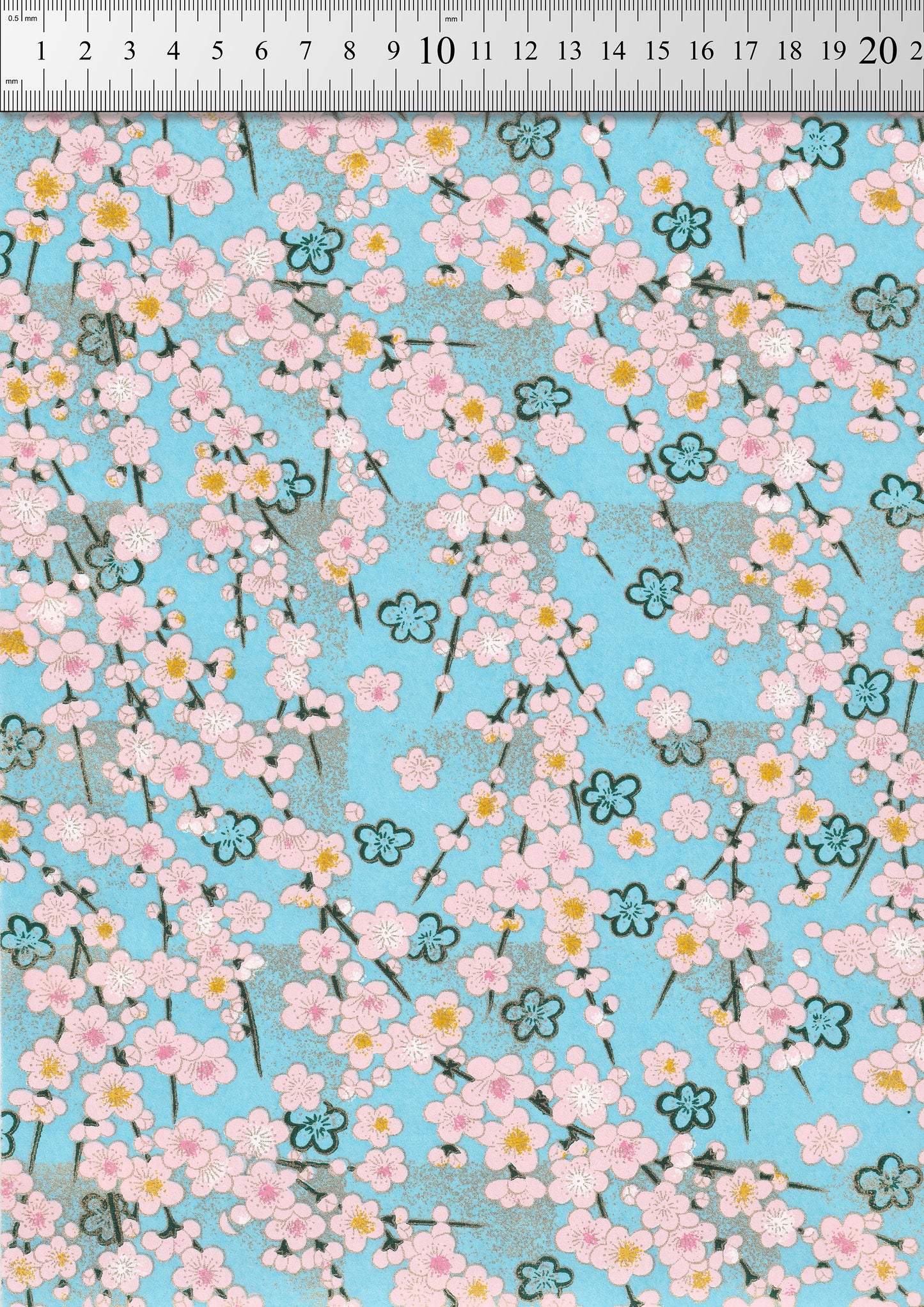 Chiyogami paper with Floral pattern with pink flowers on a blue background with a ruler for scale