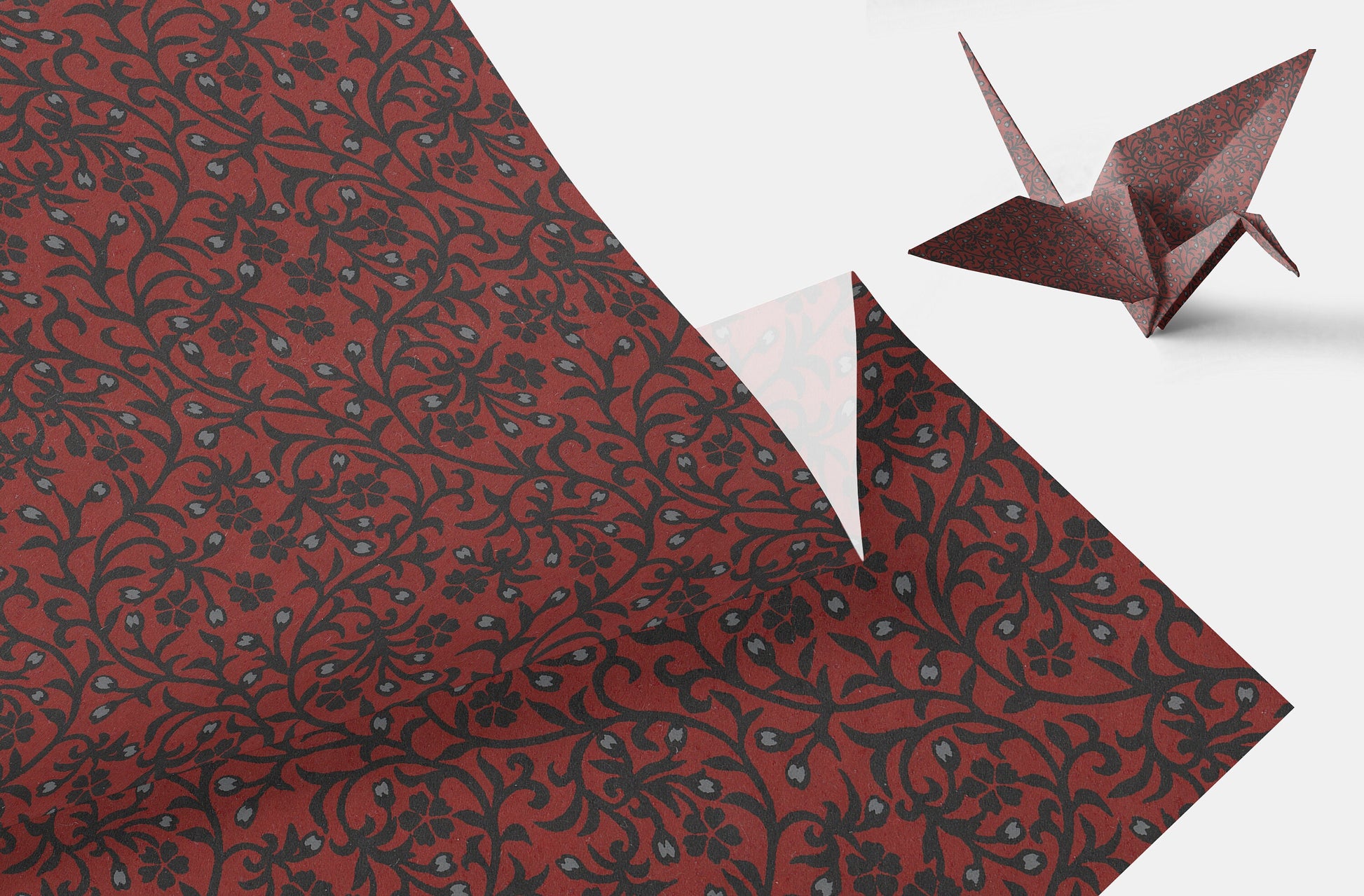 Red patterned paper with a white triangle and a brown origami crane on a white background