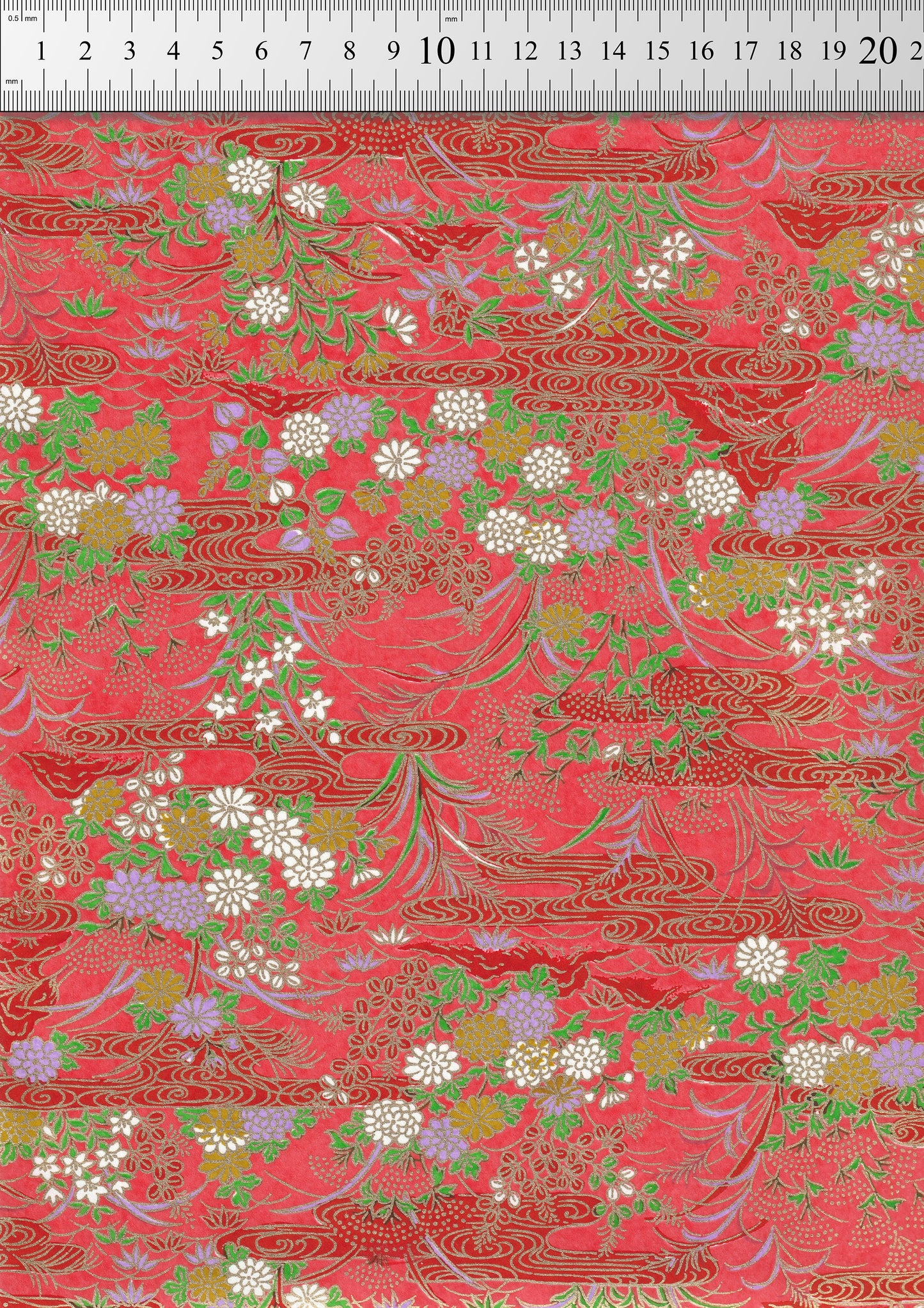 Decorative chiyogami paper with floral and leaf patterns on a red background, measured against a ruler.