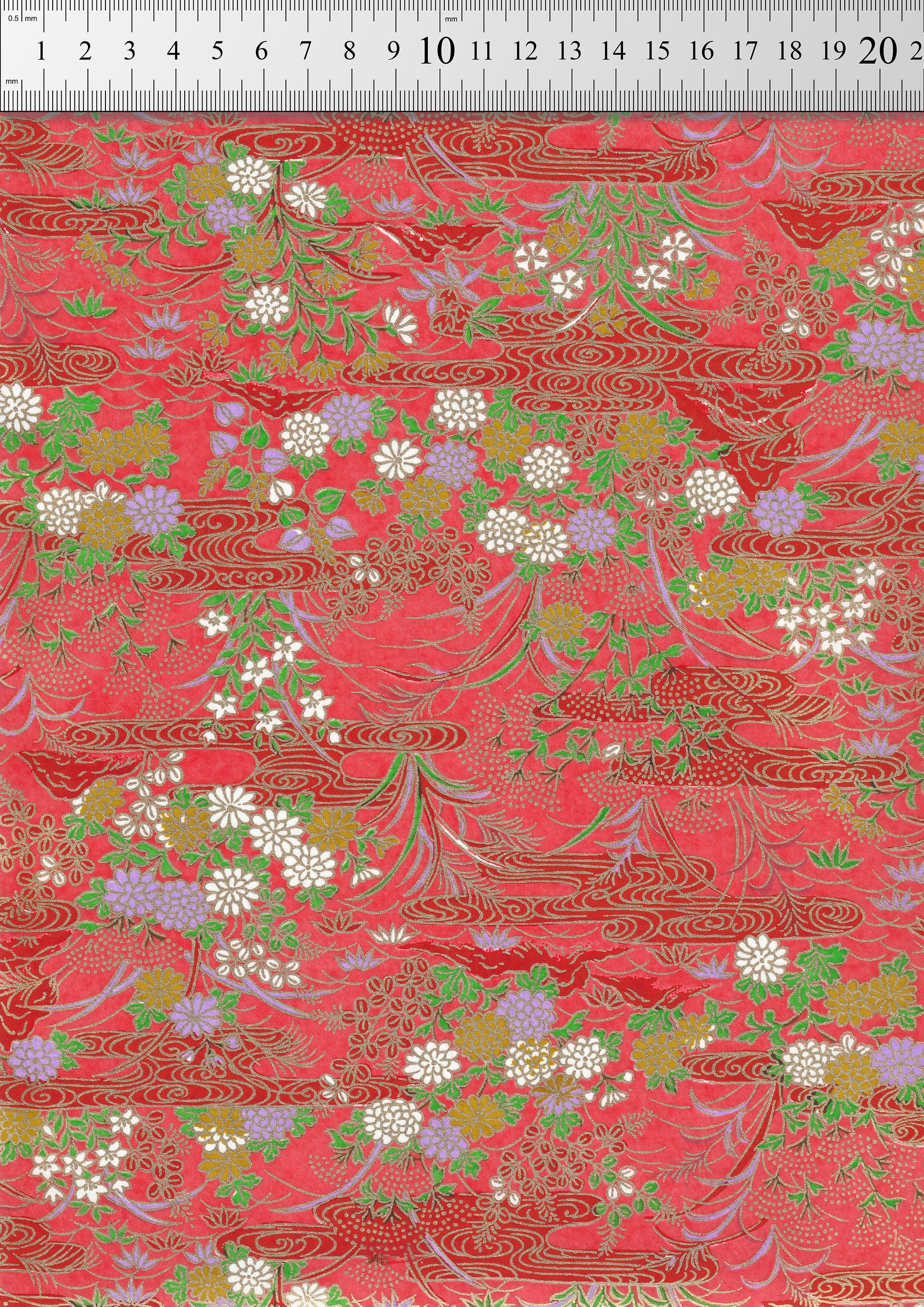 Decorative chiyogami paper with floral and leaf patterns on a red background, measured against a ruler.