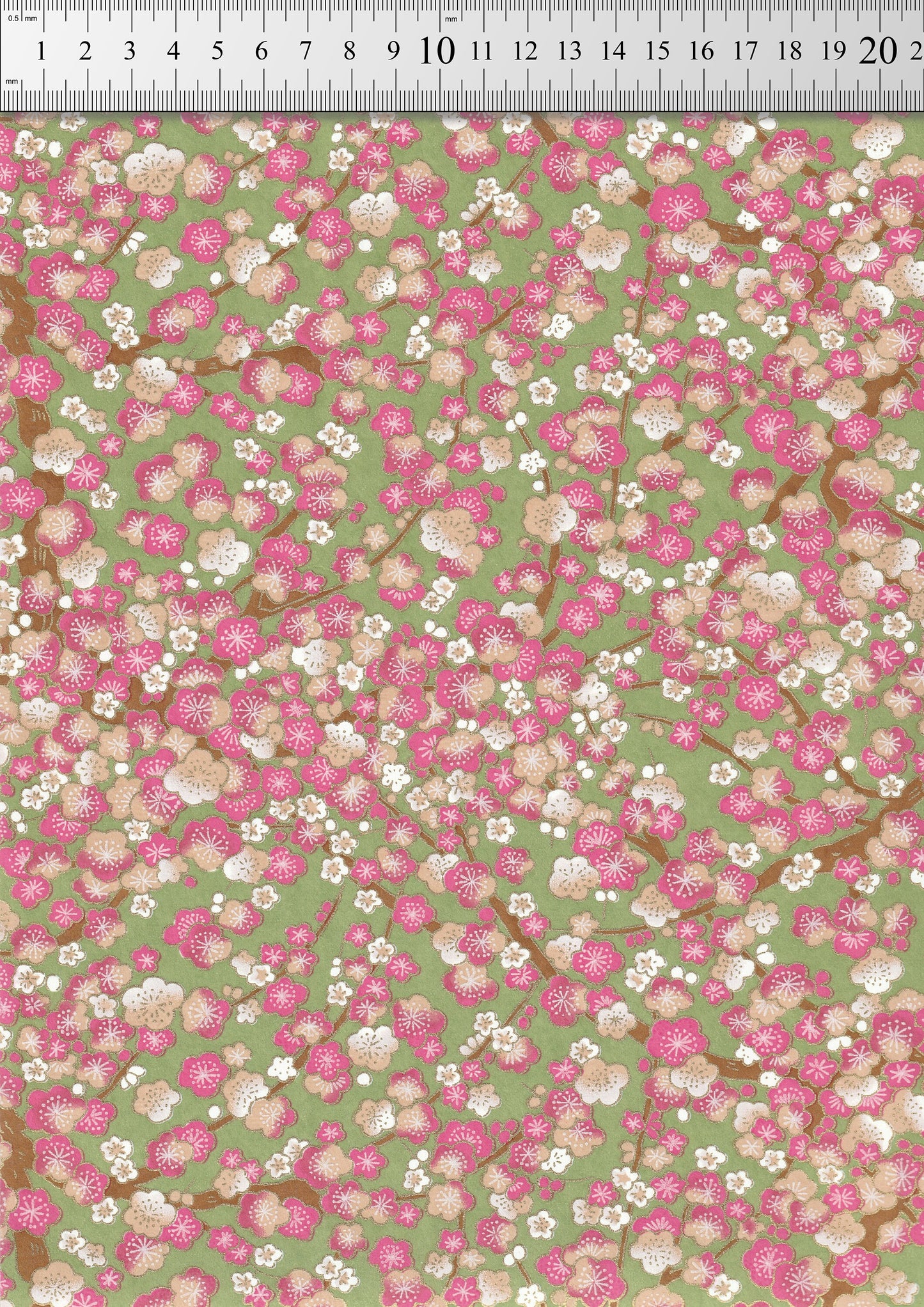 Floral pattern chiyogami paper with pink and white flowers on a green background with a ruler for scale