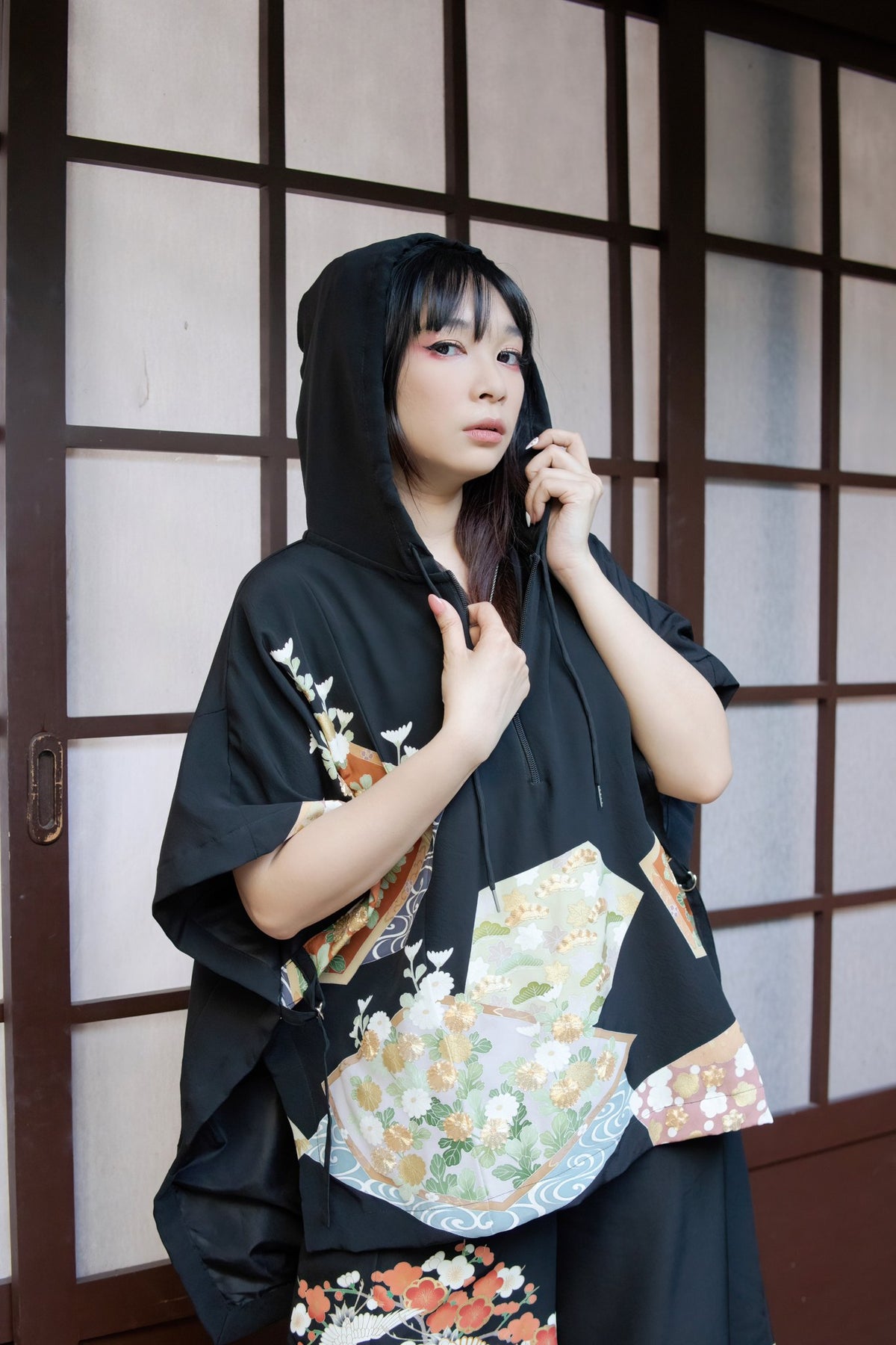 Model in a black upcycled kimono hooded poncho with a floral fan pattern by Leverras Art