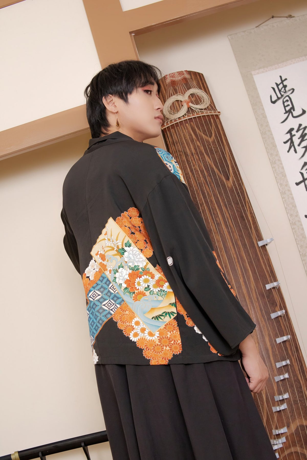 Male model in a black upcycled kimono jacket with an orange chrysanthemum pattern by Leverras Art